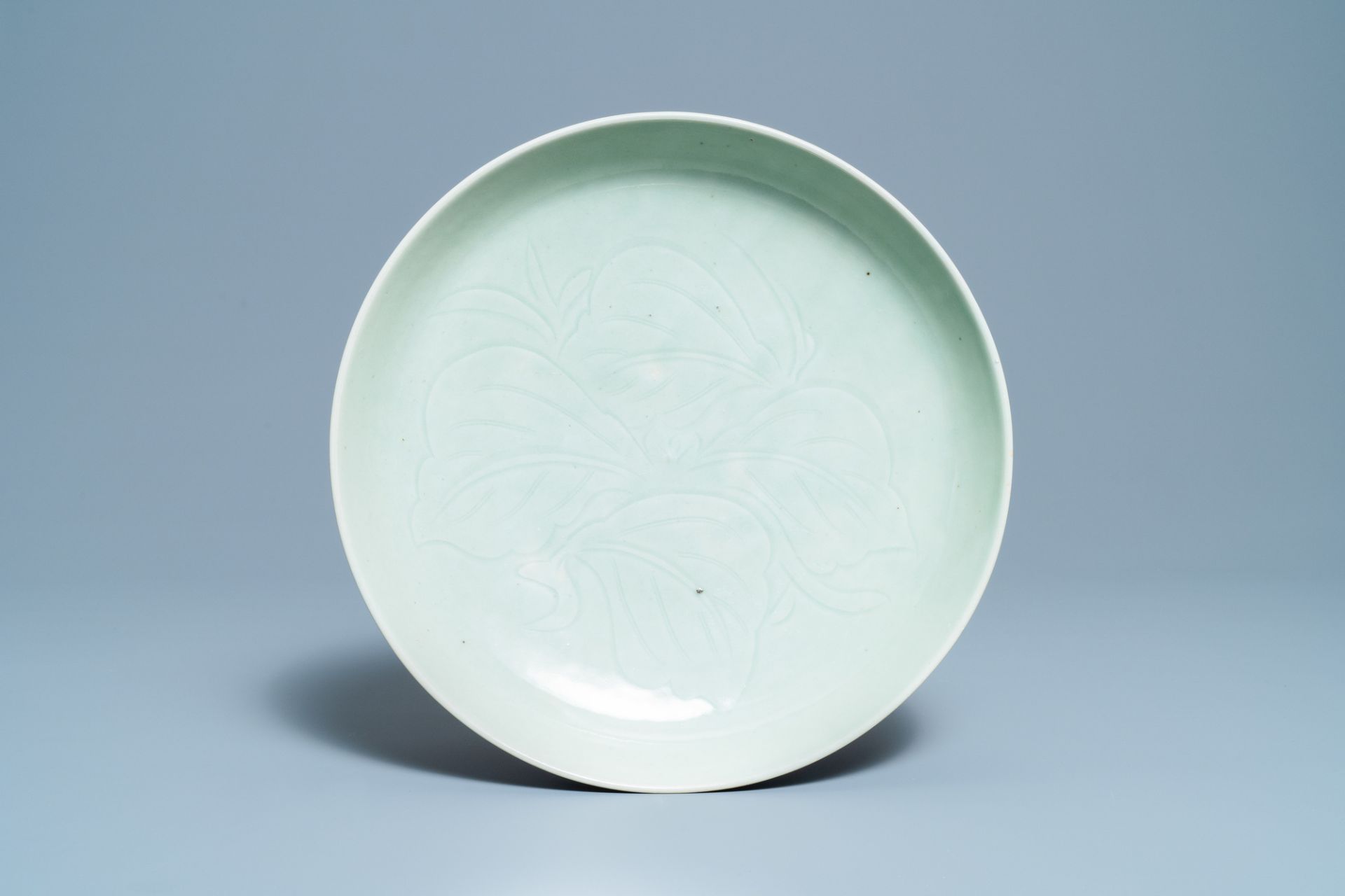 A Chinese monochrome celadon-glazed dish with underglaze floral design, 18/19th C.