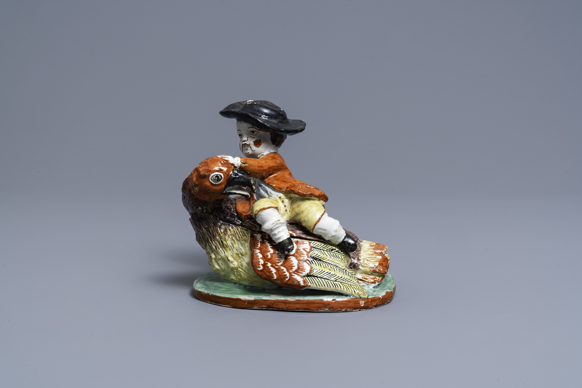 A polychrome Dutch Delft box and cover in the shape of a boy on a bird, 18th C.
