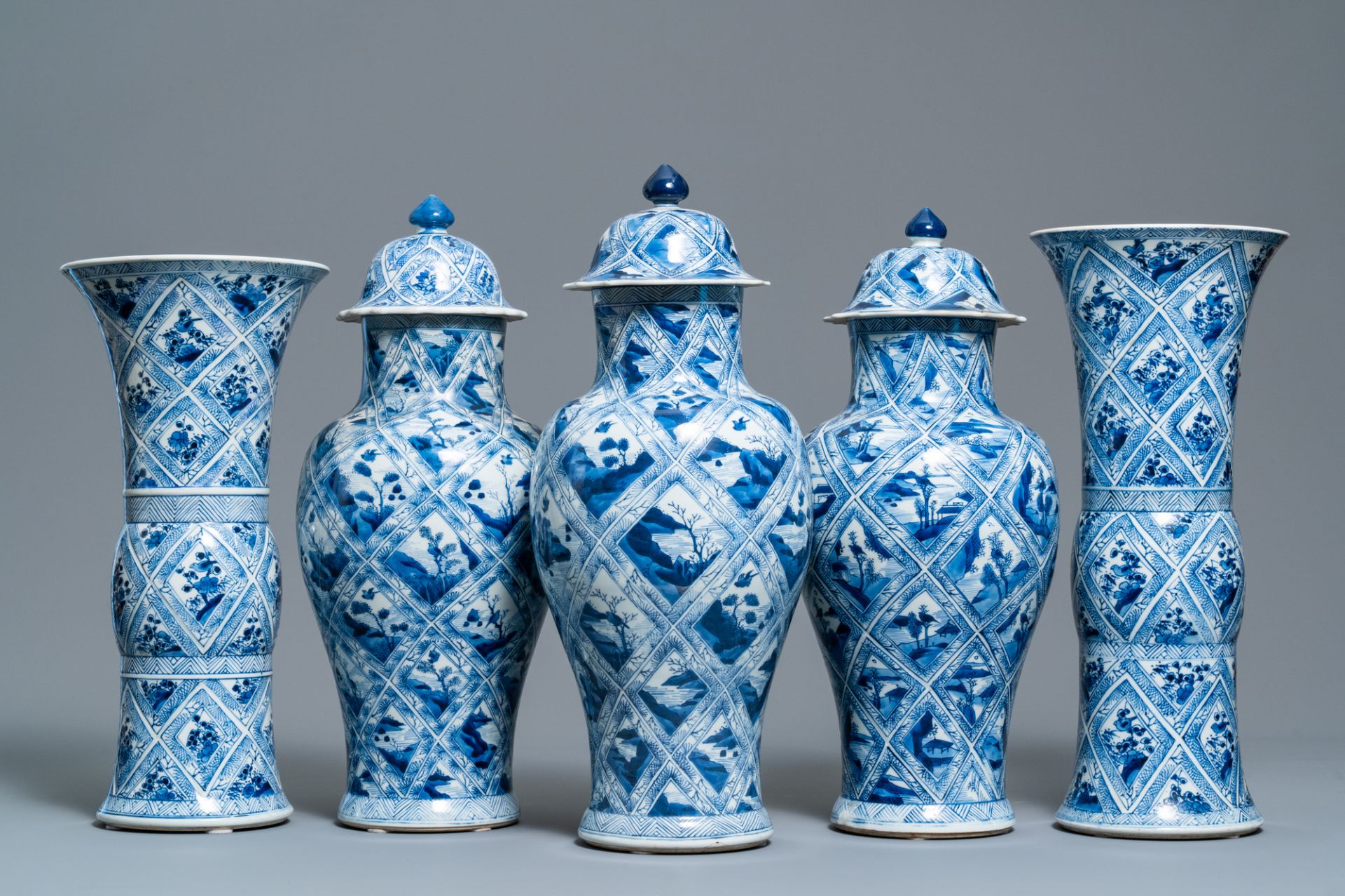 A large Chinese blue and white five-piece garniture with floral and landscape panels, Kangxi