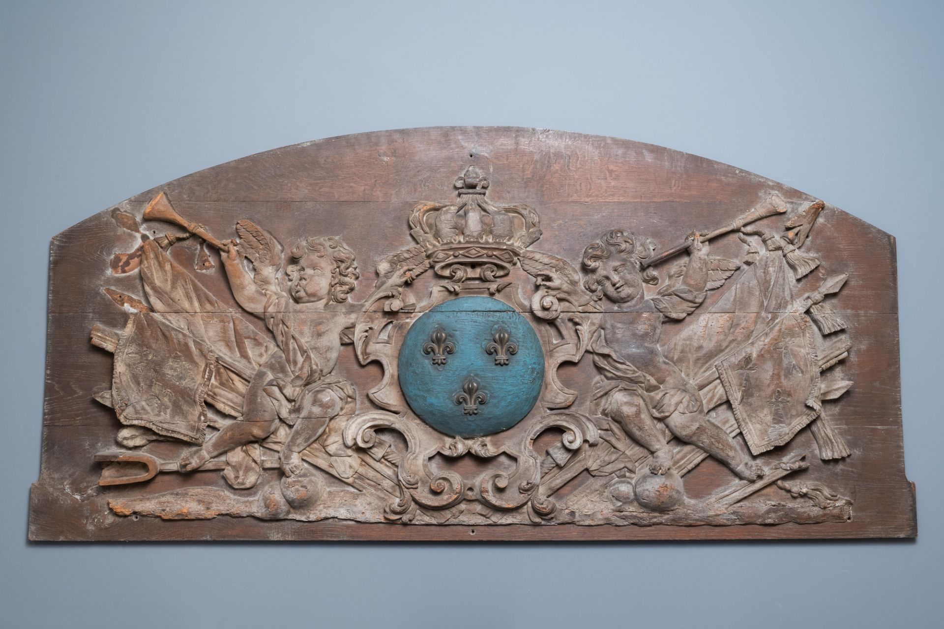 A large polychromed carved oak panel with putti and trophies flanking the royal coat of arms of Fran