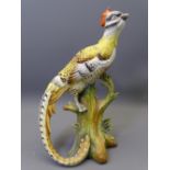 A CONTINENTAL PORCELAIN EXOTIC LONG TAILED BIRD ON A TRUNK, base unmarked, 25cms H