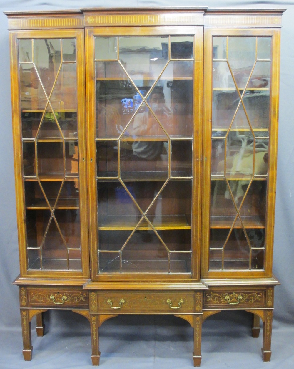 EDWARDIAN SHERATON STYLE INLAID BREAKFRONT BOOKCASE/CABINET having three lower drawers on square