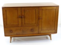 MID-CENTURY ERCOL GOLDEN ELM SIDEBOARD, model 467, fitted cupboards and apron drawer, splayed