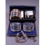 CASED & OTHER NAPKIN RINGS (5) with a hallmarked port decanter label in the shape of an anchor,