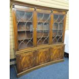 MAHOGANY CONCAVE REPRODUCTION BOOKCASE with dentil shaped cornice, over three upper glazed doors
