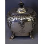 SILVER NEAR SQUARE TEA CADDY with applied floral and leaf decoration, hinge lid on four scrolled