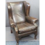 ANTIQUE STYLE BROWN LEATHER WINGBACK ARMCHAIR with foldover arms on carved knee front supports,