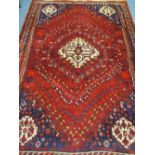 AN EASTERN STYLE RED GROUND WOOLLEN CARPET with central light colour block on a red ground with blue