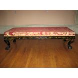 A LONG STOOL in a black lacquered chinoiserie frame on ball and claw corner supports and with red