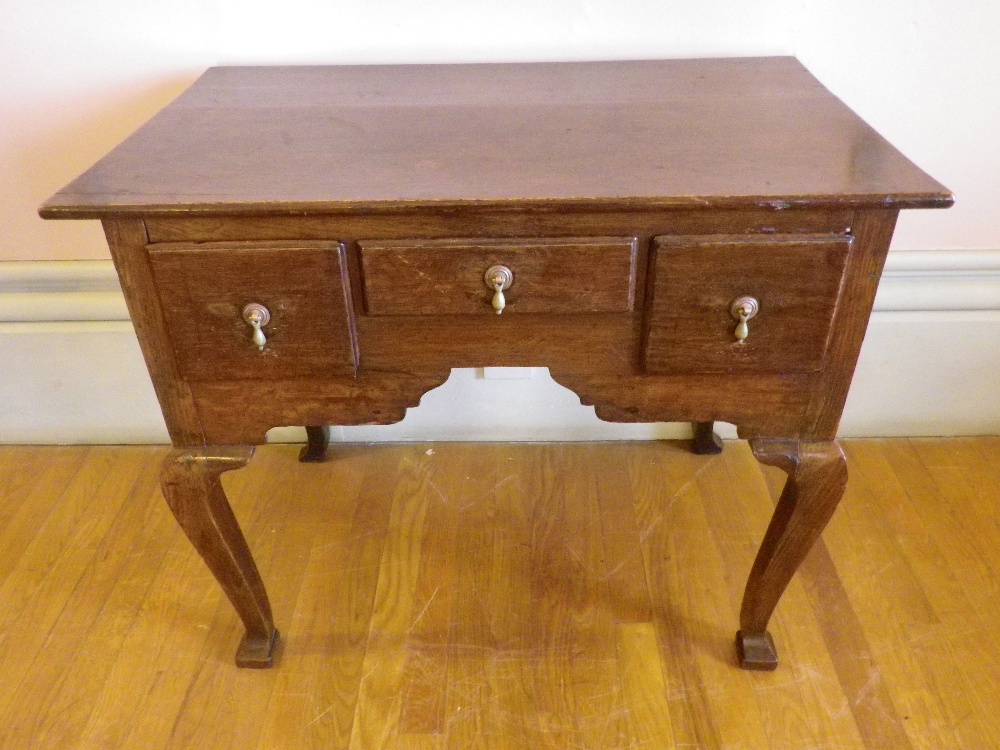 CIRCA 1820 OAK LOWBOY having two plank rectangular top over three drawers and shaped apron with