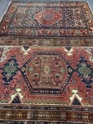 TWO EASTERN WOOLLEN CARPETS, red and blue ground with central block pattern and multi-bordered edge,