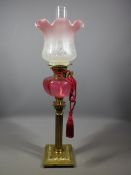 VICTORIAN OIL LAMP, brass Corinthian column base with Cranberry glass font and pink tinted frill