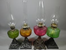 VINTAGE CAST IRON BASE OIL LAMPS (4), all with coloured glass fonts, 1 x Cranberry, 2 x Green and