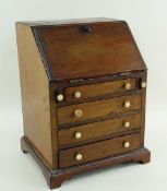 19TH CENTURY MINIATURE MAHOGANY BUREAU, angled fall with fitted interior, bracket feet, 21.5 x 18