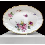 A NANTGARW PORCELAIN OVAL DISH of lobed form and decorated with a large off-centre spray of flowers,