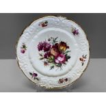 A NANTGARW PORCELAIN LONDON DECORATED PLATE having a border moulded with c-scrolls, ribbons and