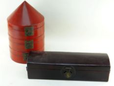 TWO CHINESE LACQUERED RED BOXES, comprising a triple tiered hat box, 46cms high, and a narrow dome-