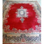 KIRMAN CARPET, indigo and ivory rectangular medallion with pendants on a plain cherry red field with
