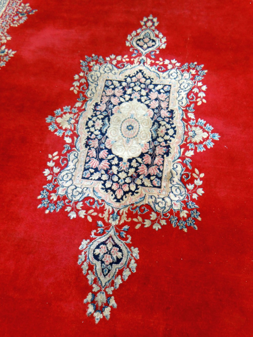 KIRMAN CARPET, indigo and ivory rectangular medallion with pendants on a plain cherry red field with - Image 5 of 11