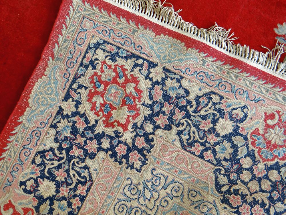 KIRMAN CARPET, indigo and ivory rectangular medallion with pendants on a plain cherry red field with - Image 10 of 11