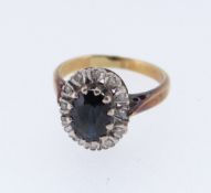 18CT GOLD SAPPHIRE & DIAMOND CLUSTER RING, the central sapphire (7 x 5mms) surrounded by twelve