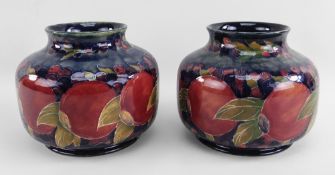 PAIR OF WILLIAM MOORCROFT POMEGRANATE VASES, circa 1916, of circular form with foot signed to the