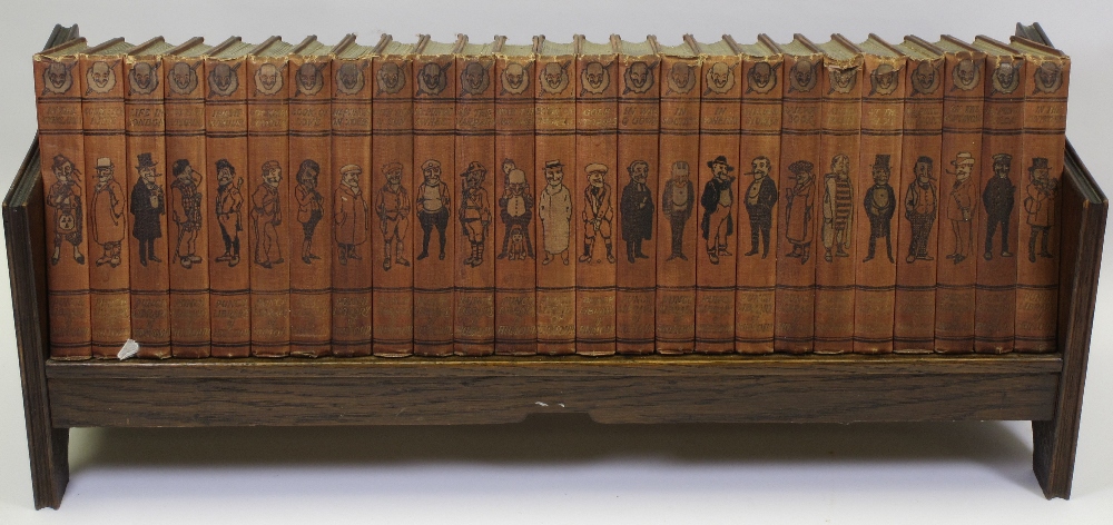 PUNCH LIBRARY OF HUMOUR on an oak bookcase stand, 25 volumes, 25cms H, 64cms W, 18cms D the stand