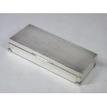 AN OBLONG ENGINE TURNED SILVER MOUNTED CIGARETTE BOX with two interior compartments and on neat