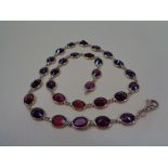 ITALIAN 18CT GOLD & GARNET NECKLACE of 29 facet cut stones, oval mounted with looped ends, 44cms