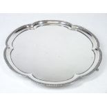 A CIRCULAR SILVER TRAY with gadrooned and shaped border on three paw supports, uninscribed,
