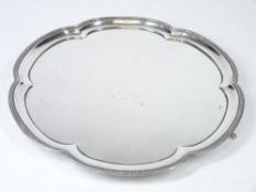 A CIRCULAR SILVER TRAY with gadrooned and shaped border on three paw supports, uninscribed,