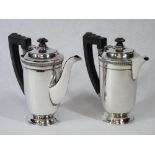 A PAIR OF SILVER COFFEE POTS - plain bodies on a pedestal base with stepped top, handles and knops