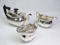 SILVER TEA SERVICE - three piece, each of plain form with feather edge rims and on four ball feet,