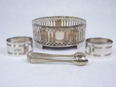 WINE BOTTLE COASTER, PAIR OF NAPKIN RINGS & A SET OF EPNS SUGAR TONGS - Chester 1911, Maker George