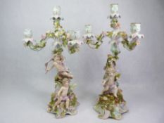 PLAUE PORCELAIN CHERUB & FLORAL ENCRUSTED CANDELABRA, A PAIR - underglazed crossed hatch in blue