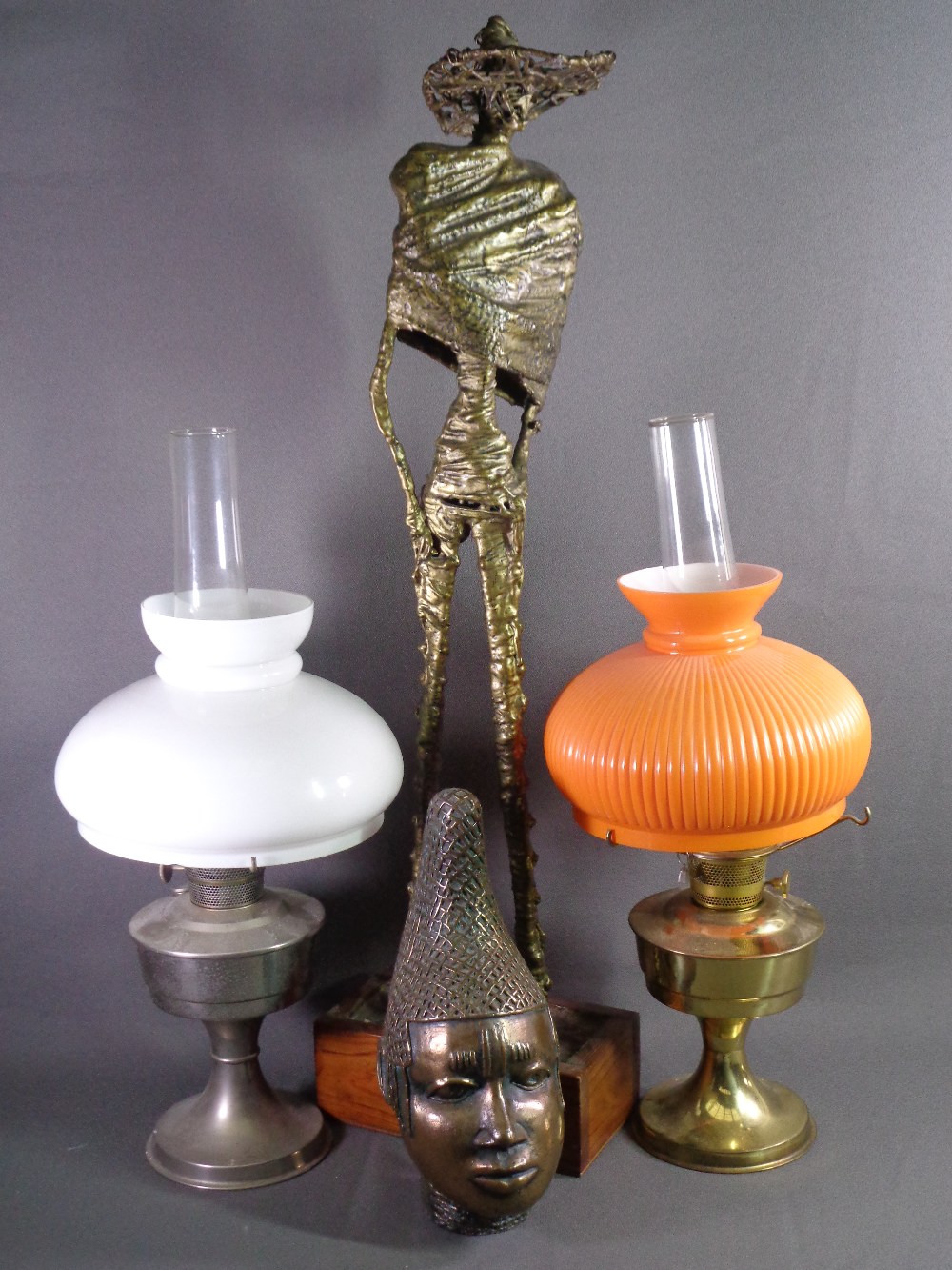 VINTAGE OIL LAMPS (2), abstract composite tall figure on a wooden plinth and a native bust