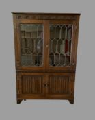LINENFOLD BOOKCASE CUPBOARD with upper leaded glass doors, 135cms H, 95cms W, 32cms D