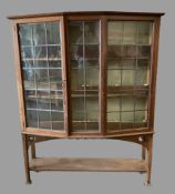 ARTS & CRAFTS STYLE BOOKCASE CUPBOARD with angular bow front and leaded glass doors, 147cms H,
