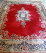 KIRMAN CARPET, indigo and ivory rectangular medallion with pendants on a plain cherry red field with