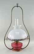 CRANBERRY GLASS & BRASS HANGING OIL LAMP with opaque glass shade and clear glass funnel, 63cms high