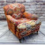 GEORGE SMITH HOWARD-STYLE ARMCHAIR, upholstered in Turkish kilim, turned legs, brass castors, labels