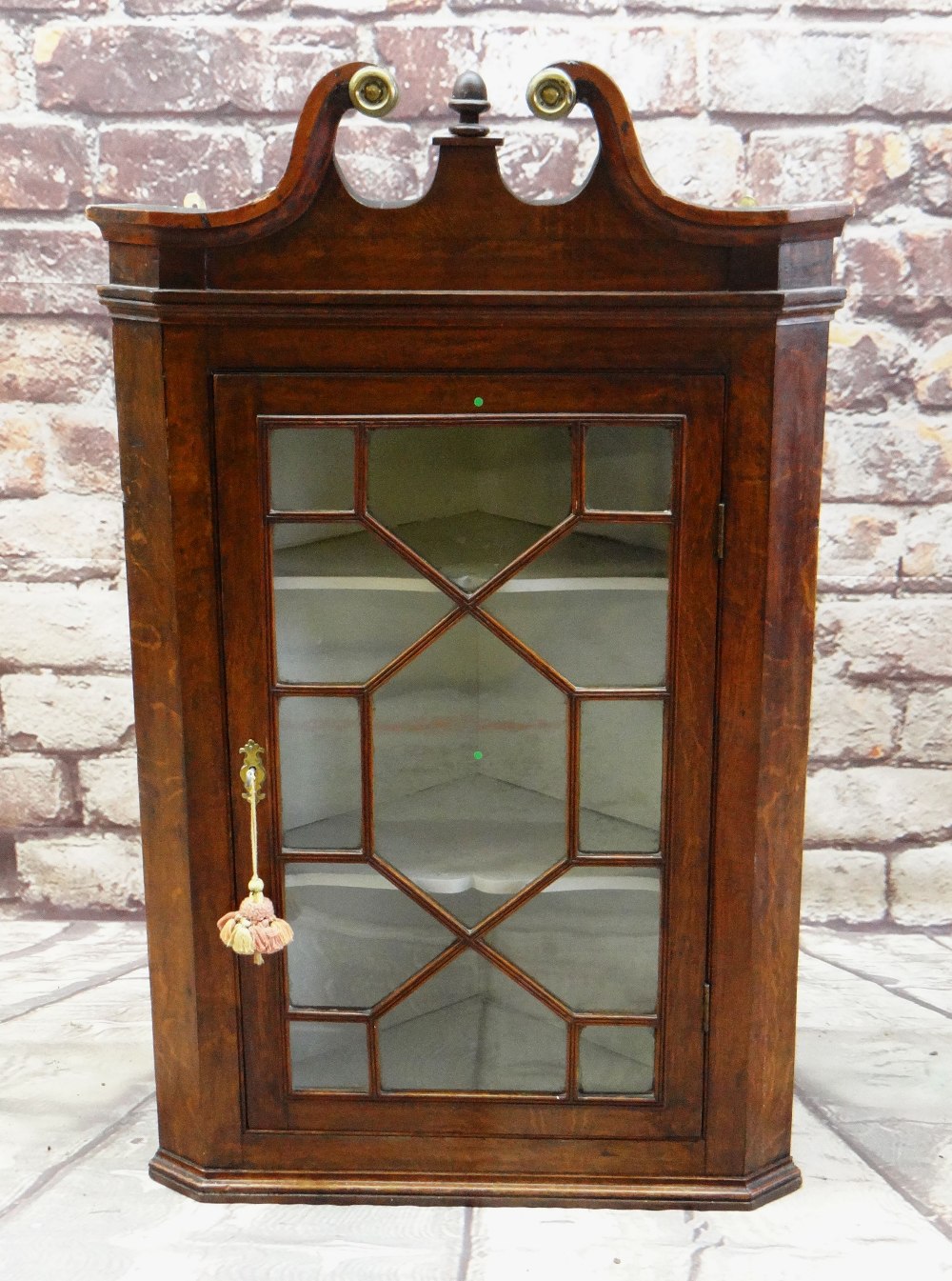 18TH CENTURY OAK HANGING CORNER CABINET, swan neck pediment with brass caps, later acorn finial,