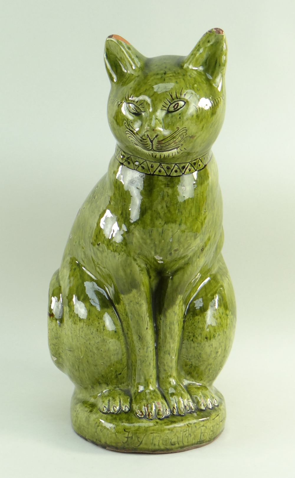 LARGE EWENNY POTTERY MODEL OF A SEATED CAT in green glaze, incised decoration, geometric design