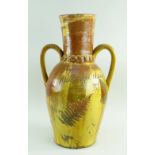 A 19TH CENTURY SLIPWARE POTTERY TWIN HANDLED VASE with elongated neck and two loop handles, clear