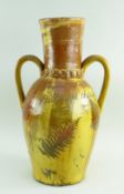 A 19TH CENTURY SLIPWARE POTTERY TWIN HANDLED VASE with elongated neck and two loop handles, clear