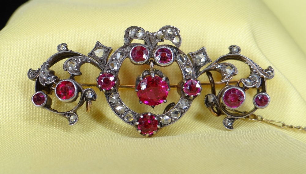 YELLOW & WHITE METAL SET DIAMOND & RUBY BAR BROOCH of naturalistic bow, scroll and leaf design, 11.