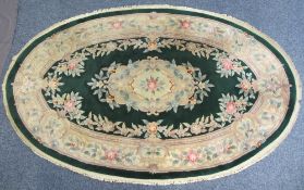 OVAL CHINESE WASHED WOOLLEN RUG - green ground with bold floral design and tasselled edging, 260 x