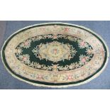 OVAL CHINESE WASHED WOOLLEN RUG - green ground with bold floral design and tasselled edging, 260 x