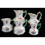 FIVE SWANSEA POTTERY JUGS including graduated trio, all with green twig-handles, enamelled flowers