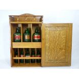 OAK MEDICINE BOTTLE CABINET containing eight green glass Latin labelled bottles, all having ribbed